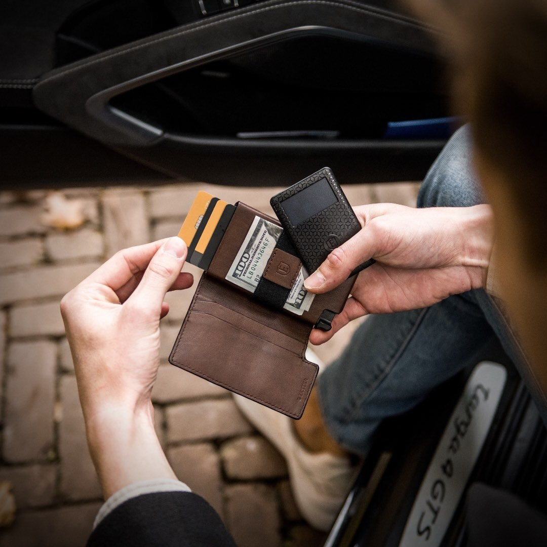 Person’s hands holding an open RFID blocking Parliament wallet with cash in the cash band and a smart tracker card