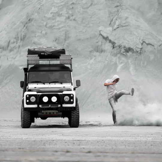 Jeep defender with man kicking the sand