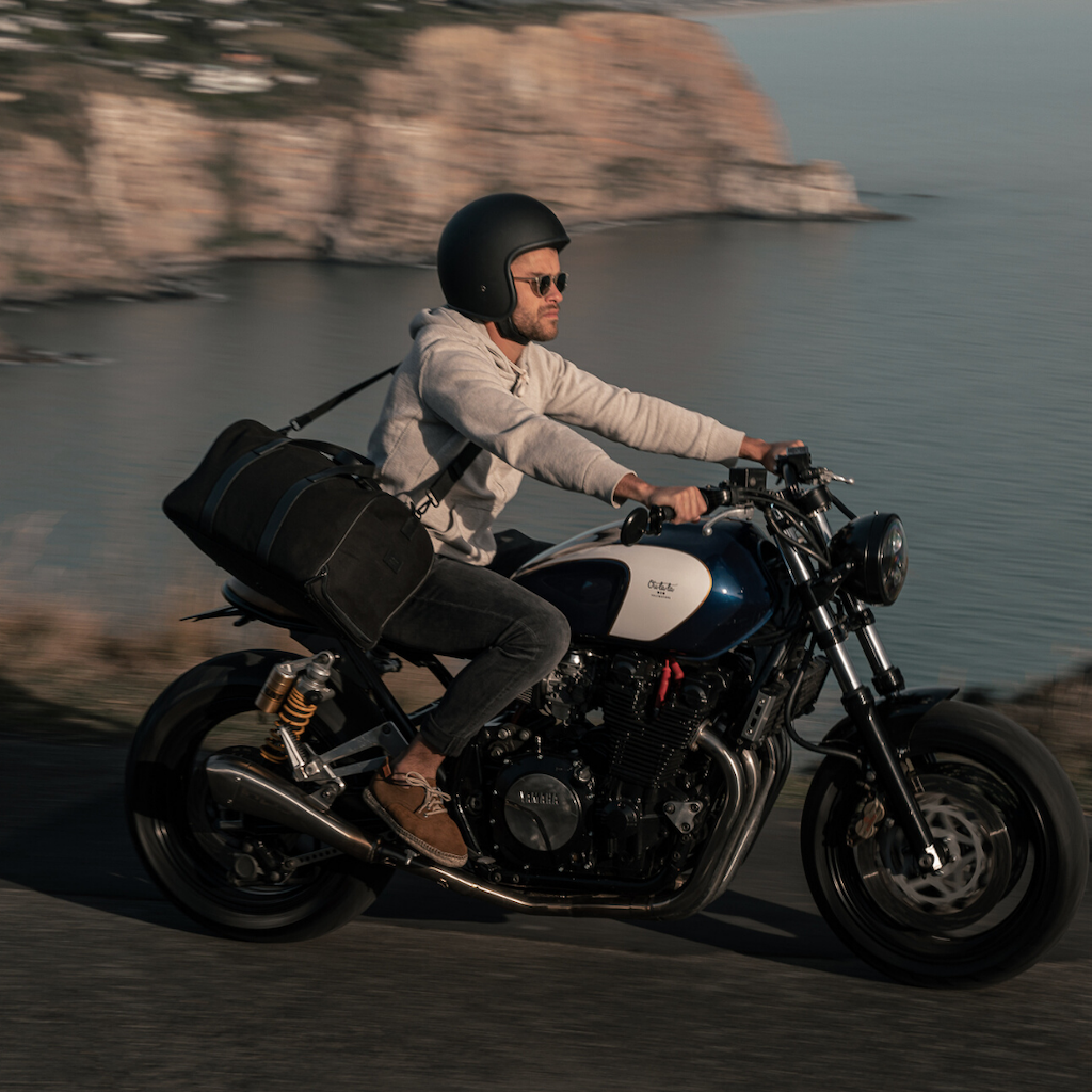 motorcycling biker with weekender bag riding