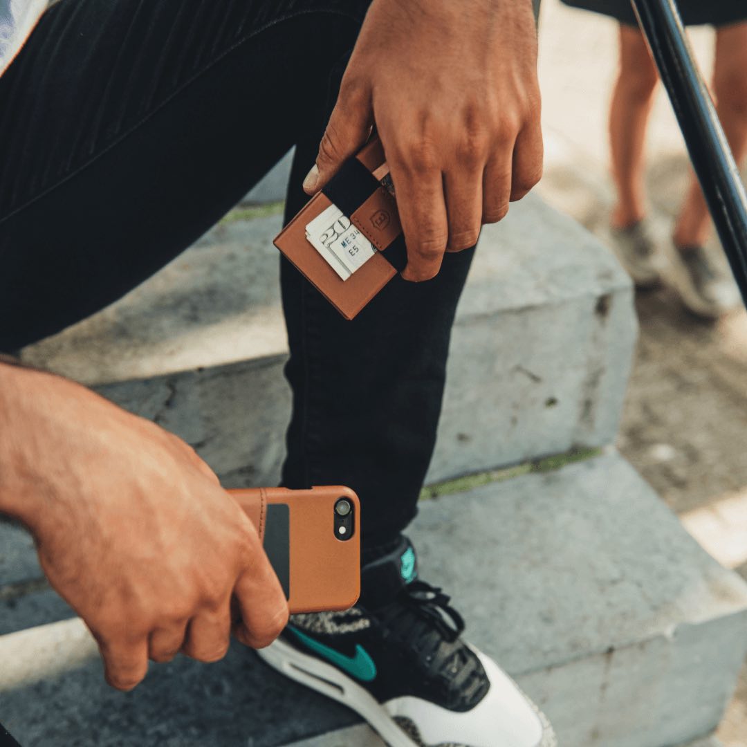 Man displaying Ekster Senate wallet and iPhone case in a shade of brown